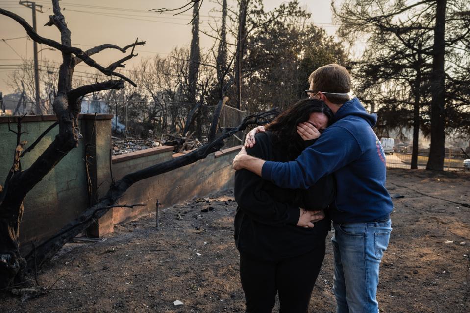 A man comforts his daughter on the charred ruins of their family home burned in the Eaton Fire in Altadena, California, January 9, 2025.