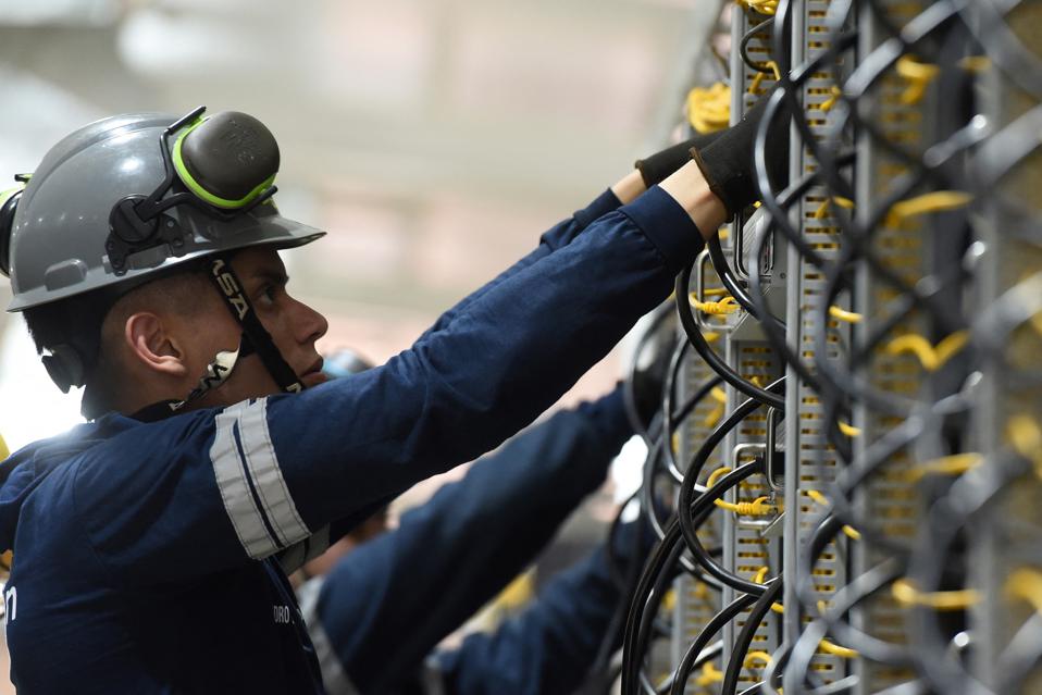 Technicians inspect bitcoin mining rigs.